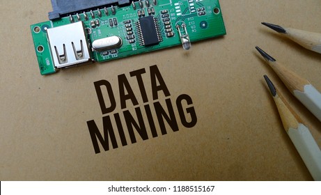 Data mining text memo written on a brown craft paper as background with pencils and board circuit