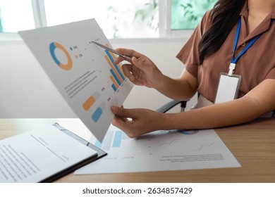 Data Presentation. Professional analyzing financial reports and graphs in a modern office.