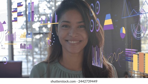 Data processing on interface with charts over happy biracial casual businesswoman smiling in office. Business, data, digital interface, connection and communication digitally generated image.