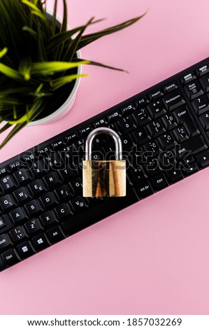 Data protection minimal concept. Flat lay setup on pink backdrop. Lock and keyboard.