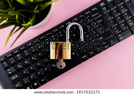 Data protection minimal concept. Flat lay setup on pink backdrop. Lock and keyboard.