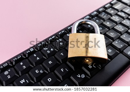 Data protection minimal concept. Flat lay setup on pink backdrop. Lock and keyboard.