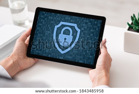 Data Protection And Privacy Concept. Over the shoulder view of woman holding and using digital tablet, padlock icon with binary code on the screen. Personal information, fraud and online crime