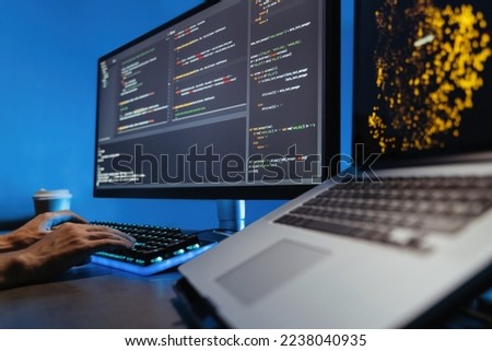 Data science concept. No face image of male hands typing on keyboard, writing html code for website, sitting at desk with pc and laptop, working on project in software development company