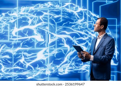 Data scientist analyzes AI brain models on tablet with large digital brain displayed behind. IT expert using machine learning to better understand and develop artificial intelligence - Powered by Shutterstock