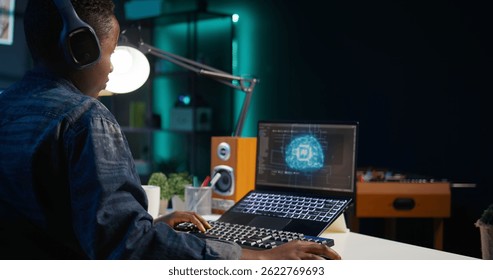 Data scientist using laptop, updating artificial intelligence machine learning algorithms, writing code scripts. Teleworking IT specialist in apartment office uses programming to upgrade AI, camera B