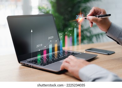 Data statistical index graph on virtual screen concept, Businessman use laptop show development graph and point the target of business work and calculates financial data for long-term investments