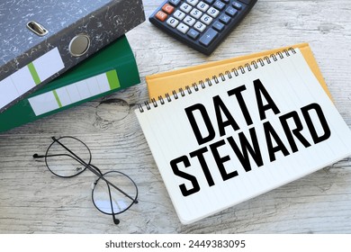 DATA STEWARD torn page from a notebook on a gray notepad. folders on the table