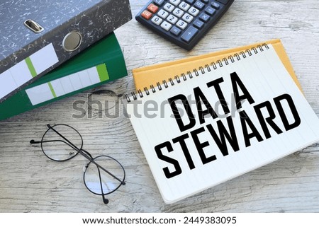 DATA STEWARD torn page from a notebook on a gray notepad. folders on the table