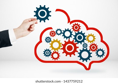 Data storage network technology concept. Businessman hand with creative cloud and cogs on subtle background