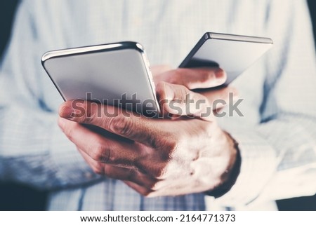 Data transfer between two mobile phones, adult male holding two smartphones