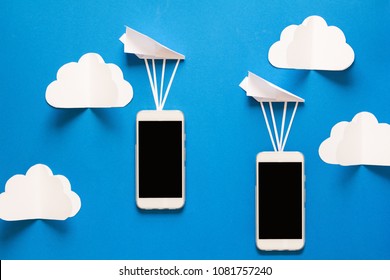 Data transfer concept. Message passing. Two mobile smartphones and paper airplanes on blue background. Origami. Paper cut.