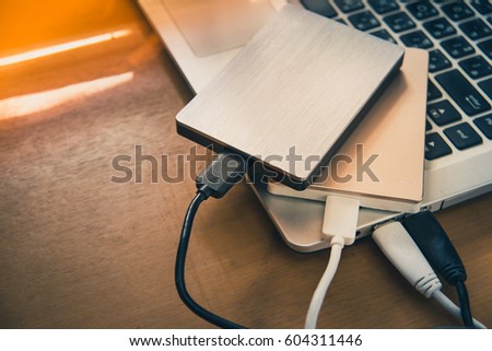 Data transfer from laptop computer to external hard disk for backup files and important information using USB 3.0 connection, wooden table background.