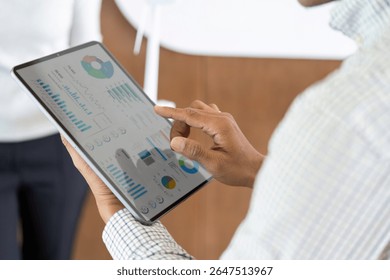 Data Visualization and Insights. Professional analyzing business metrics on tablet in modern office.
