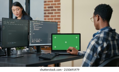 Database Designer Writing Code Using Laptop With Green Screen Chroma Key Mockup Sitting At Desk In Busy Developers Agency. Programer Looking At Multiple Screens With Programming Language.