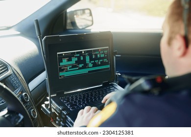 Base de datos, laptop y un oficial de policía en un auto para seguridad, ley urbana y datos de seguridad mientras trabaja. Protector, programación y profesional de protección masculina con un sistema informático para hackear en el transporte