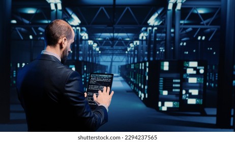 Datacenter engineer inspecting working server computers with web information on tablet, future digitalization. Modern IT administrator running diagnostics on networking connection. Tripod shot.