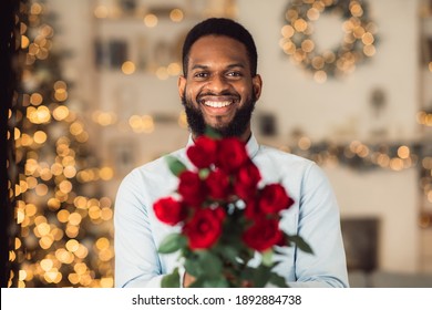 Date Concept. Portrait Of Happy Bearded Young Black Guy Holding Bunch Of Fresh Flowers And Giving Bouquet Of Red Roses To Camera. Celebrating Holiday, Anniversary, Valentine's Day, 8 March
