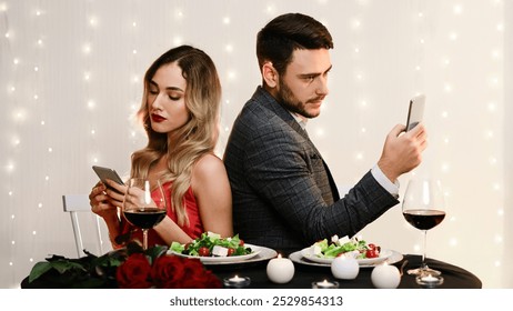Date Fail. Bored Couple Using Smartphones Sitting Back To Back On Romantic Dinner In Restaurant, Ignoring Each Other.