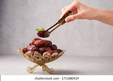 Date Fruits or Kurma in the bronze plate at grey concrete background. Dates and water is Ramadan meal. Ramazan Iftar food.