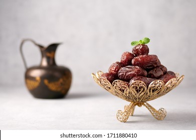 Date Fruits or Kurma in vintage arabic dish and jug of water at grey concrete background. Dates and water is Ramadan meal. Ramazan Iftar food.