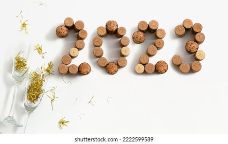 Date of the New Year 2023 made of champagne and wine corks. Happy New year holidays card with glasses and golden confetti on white background. Party time, flat lay idea for banner - Powered by Shutterstock