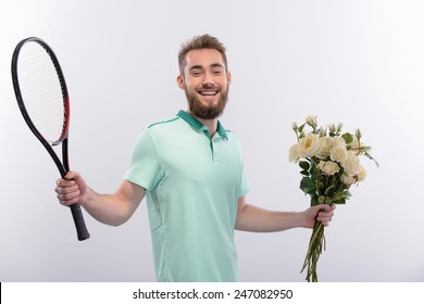 Date On The Tennis Court. Handsome Young Man Holding Tennis Racket In One Hand And Flowers In The Other While Standing Isolated On White Background