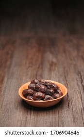 Dates in a brown cup with wood background.