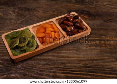 Dates, dried apricots and kiwis in a Compartmental dish on a dark wooden table. Stock photo © 