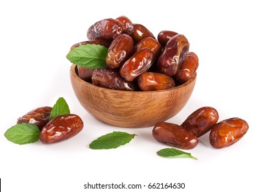 Dates in a wooden bowl with a mint leaf isolated on white background - Shutterstock ID 662164630