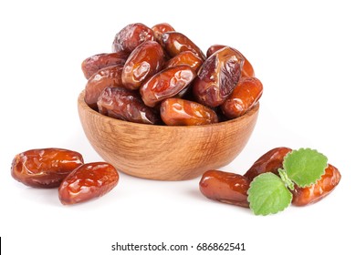 Dates in a wooden bowl with a mint leaf isolated on white background