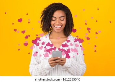Dating App. Afro millennial girl using online service, receiving love sms with hearts flying away from phone screen