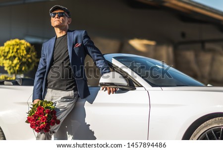 Dating Caucasian Senior in His 60s with Roses in Front of His Convertible Car. 