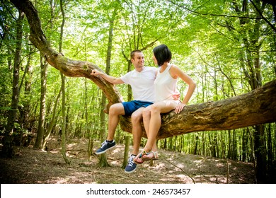 Dating in nature - young couple sitting together on big tree - Powered by Shutterstock