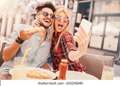 Dating in pizzeria. Handsome smiling couple enjoying in pizza, having fun together. Consumerism, food, lifestyle concept