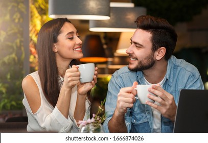 Dating. Young Couple Tasting Coffee Drinks Enjoying Flirt And Conversation During Weekend Date Sitting In Cozy Cafe