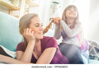 Daughter braiding mother's long hair, happy loving family at home - Powered by Shutterstock