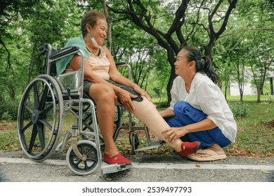 Daughter caring an elderly disabled woman who has had her legs amputated and is in a wheelchair and is being treated diabetes holds prosthetic leg to be fitted relieve her disability. - Powered by Shutterstock