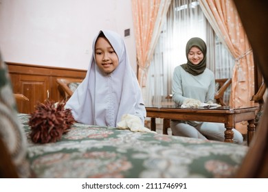 Daughter Cleaning Chair With Duster With Mother In Living Room