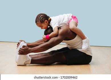 Daughter climbes on her father's neck as he stretches his back and knees on the floor. They having fun, entertaining themselves in isolation. - Powered by Shutterstock