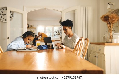 Daughter doing homework, mother working on laptop - Powered by Shutterstock