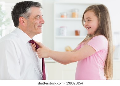 Daughter fixing fathers tie in the kitchen before work