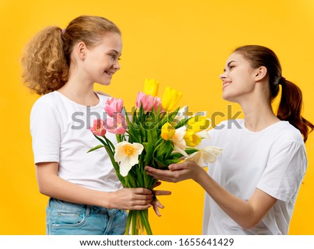 Daughter gives mom flowers as holiday gift, fun yellow background