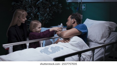 Daughter giving water to dad in hospital bed. - Powered by Shutterstock