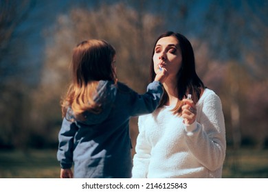 
Daughter Helping Mom Applying Lip Gloss Outdoors. Cute Little Girl Putting Lipstick On Mom
