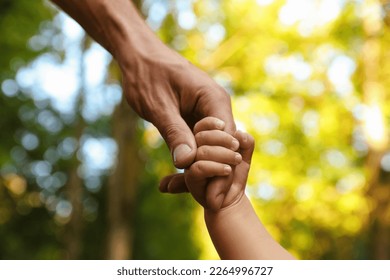 Daughter holding father's hand outdoors, closeup. Happy family - Powered by Shutterstock