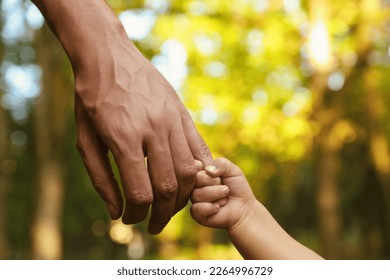 Daughter holding father's hand outdoors, closeup. Happy family - Powered by Shutterstock