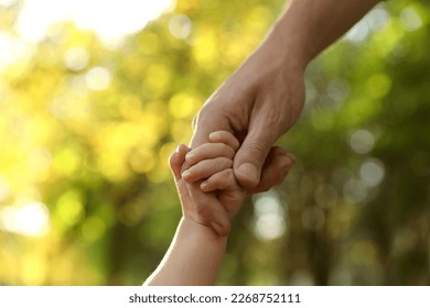 Daughter holding father's hand outdoors, closeup. Happy family - Powered by Shutterstock