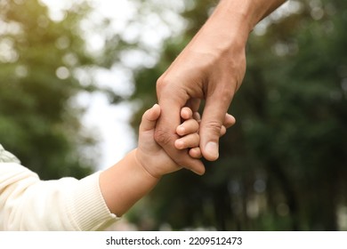 Daughter holding father's hand in park, closeup. Happy family - Powered by Shutterstock