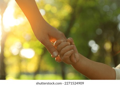 Daughter holding mother's hand outdoors, closeup. Happy family - Powered by Shutterstock